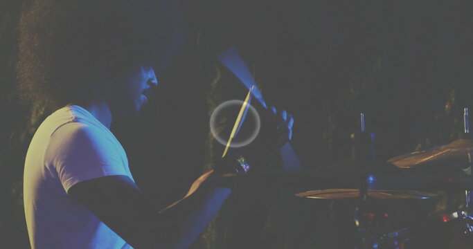 Indian percussionist wearing white t-shirt playing cabasa shaker and cymbals on stage, copy space