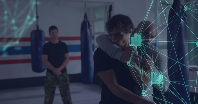 Demonstrating instructor applying hold on student in martial arts dojo with punching bags and mats - Powered by Adobe