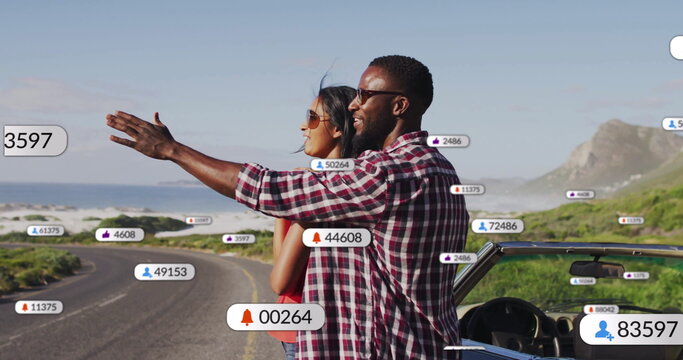 Pointing couple admiring horizon on winding coastal road, with convertible and notification icons