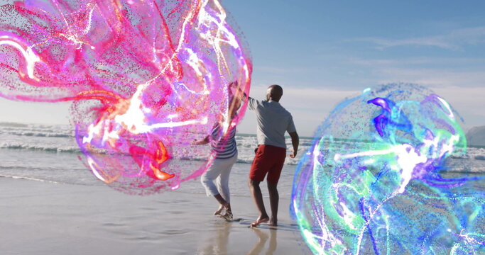 Dancing mature couple reaching toward swirling energy orbs at beach shore, with pink and blue hues