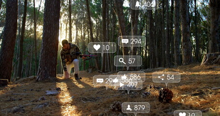 Crouching man wearing camo grabbing cone in pine forest with rifle, social media icons, copy space