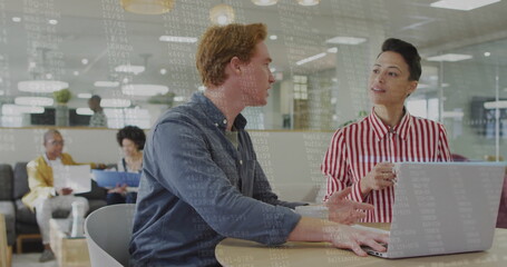 Collaborating White man and female colleague working on laptop at office lounge, with notebooks