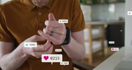 Adjusting senior man twisting ring on finger at home, with laptop, floating smartwatch metrics