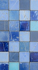 A beautiful mosaic background created from a grid of assorted square glazed ceramic tiles in various shades of blue and indigo
