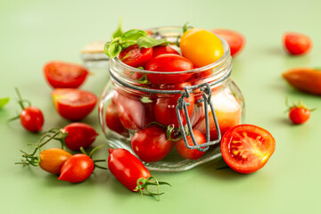 Cherry tomatoes in glass jar with basil leaves