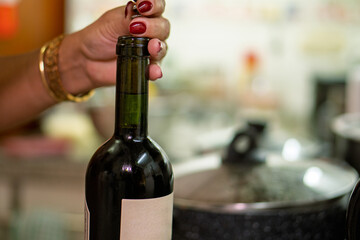 Woman uncorking bottle of red wine in kitchen