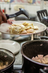 Chef placing cooked ravioli on plate in kitchen