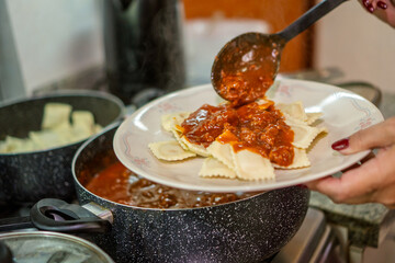 Chef pouring red meat sauce on ravioli for lunch preparation