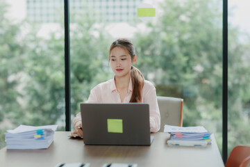 Asian female office worker focused on her tasks, showing dedication and professionalism.