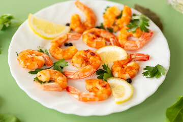 Appetizing seafood in a plate isolated on green, with lemon and herbs