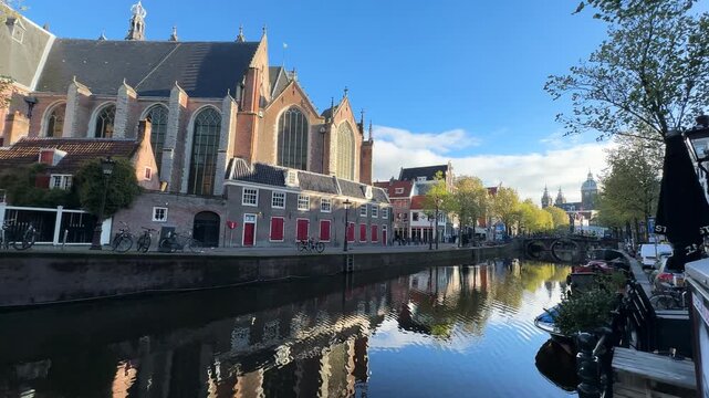 Facades of old historic Houses over canal water with Oude Kerk, Amsterdam, Netherlands