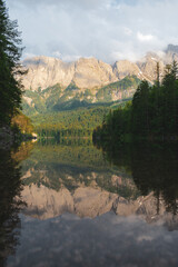 Peaceful alpine lake with crystal-clear reflection of mountains and surrounding forest under soft light. A tranquil and inspiring scene from Bavaria, Germany.