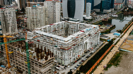 Cranes working on a construction site, modern buildings and a lake are visible in this aerial view...