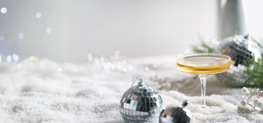 Christmas and New Year celebration with champagne. New Year holiday decorated table. Festive New Year champagne and silver baubles. Close up. Christmas greeting card with copy space.