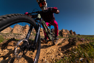 Wide angle shot from below of a cyclist in gear and protection quickly descending, feeling like...