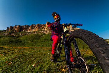 Obraz premium Front view wide angle of mountain bike and man in mountains against mountain range and hills with clouds and blue sky. Extreme sports concept, relaxation during training