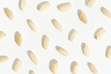 Close up of uncooked rice grains on white surface in patterned arrangement.