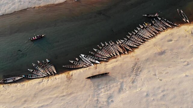 Jaflong, Bangladesh - 21 August 2025: Aerial view of numerous boats lined along the sandy riverbank, contrasting with the flowing water.
