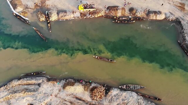 Jaflong, Bangladesh - 21 August 2025: Aerial view of boats dotting a river with contrasting water colors, sandy banks, and a truck, showcasing a bustling river scene.