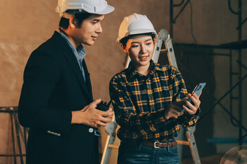Construction manager and engineer dressed in orange work vests and hard helmets explore...