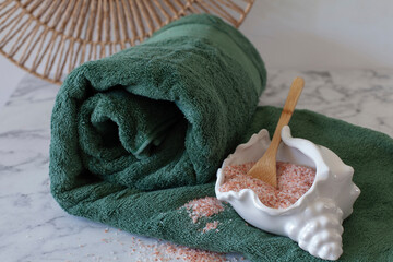 Pink Himalayan salt in shell bowl on green towel, natural spa and wellness concept
