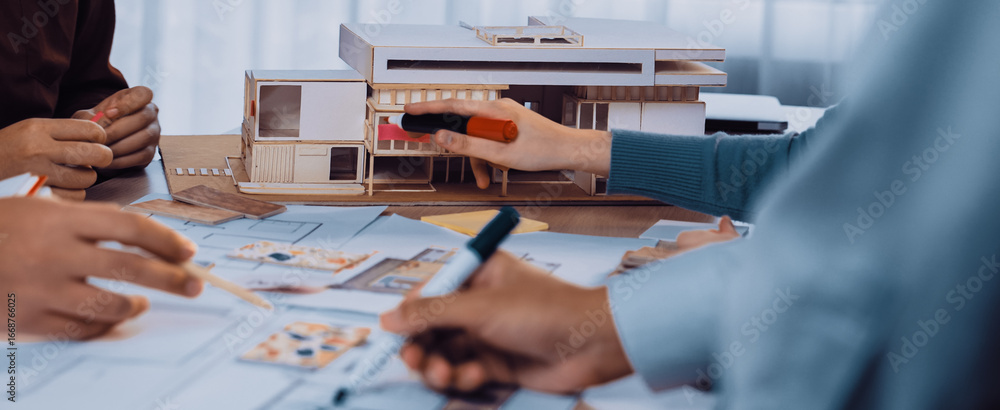 Poster a vibrant collaboration scene featuring architects working on sketches and a detailed model, emphasi