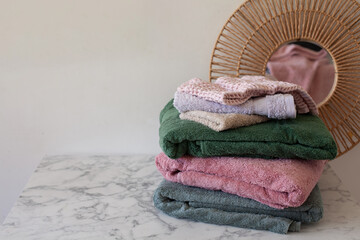 Soft pastel bath towels folded and stacked, spa concept copy space