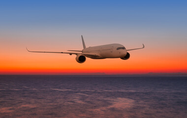 Airplane flying over tropical sea at sunset