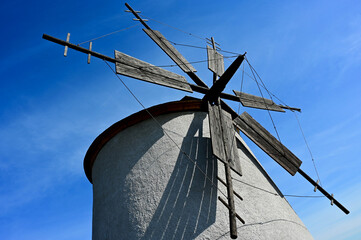 old windmill in closup abstract view. drum shape structure, sloped shingle roof. wood blades...