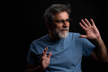 Happy man posing with low key lighting on dark background, portrait concept