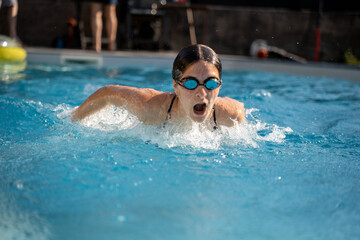Young woman swimming butterfly stroke in pool, fitness and active lifestyle