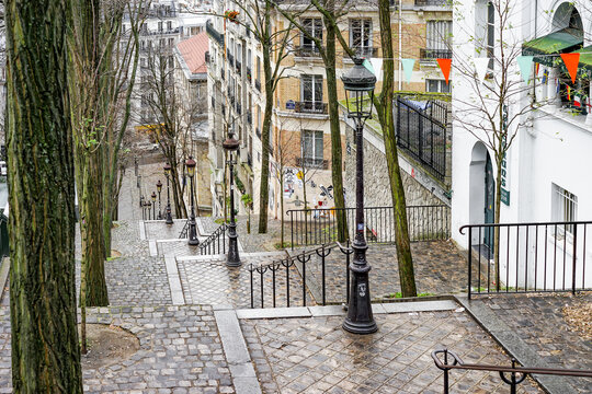 Fototapeta A street scene in Montmartre Paris France with a brick walkway and a row of lamp posts