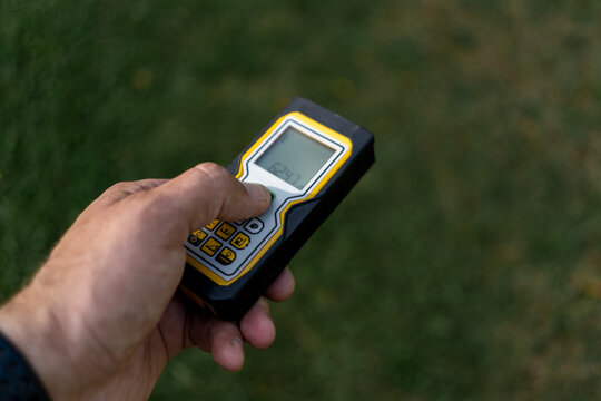 A hand with a laser rangefinder.A laser measuring tape for measuring the distance.