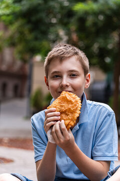 Close-up portrait of a smiling teenage boy eating a traditional Fried meat pie (Chebureki),  Tbilisi, Georgia