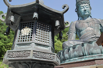 sculpted lantern and statue of buddha in a buddhist temple (showa daibutsu buddha) in aomori in japan 
