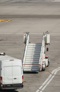 Airstairs and a van parked on an empty runway waiting for a plane to land
