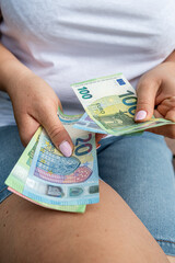 Female hands counting euro bills while sitting on a bench, personal finance and cash concept