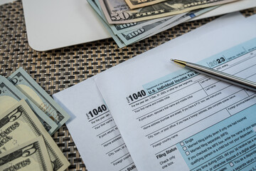 US Dollars with Tax Form 1040 and Laptop – Financial Planning and Income Report Concept