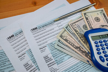 U.S. tax return forms with cash, pen, and calculator for annual income reporting 2025