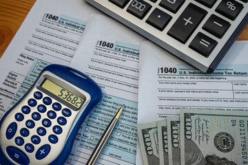 Tax preparation with 1040 forms, pen, and US dollars during annual filing season
