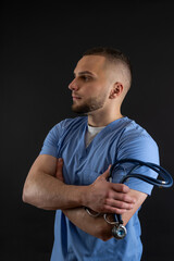 Young doctor man in blue uniform with stethoscope posign at studio. Medical worker