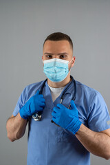 Young doctor man in blue uniform with stethoscope posign at studio. Medical worker