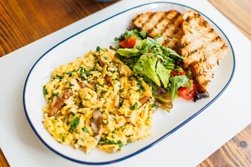 Delicious breakfast plate with scrambled eggs, greens, and grilled toast served at a cozy cafe