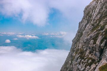 Stunning panoramic view of a cable car ascending Mount Pilatus in the Swiss Alps. The bright red gondola contrasts beautifully with the rugged mountain cliffs, lush green slopes, and distant snow-capp © Breg