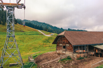 Stunning panoramic view of a cable car ascending Mount Pilatus in the Swiss Alps. The bright red gondola contrasts beautifully with the rugged mountain cliffs, lush green slopes, and distant snow-capp © Breg