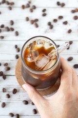 Hand is holding glass of iced coffee.