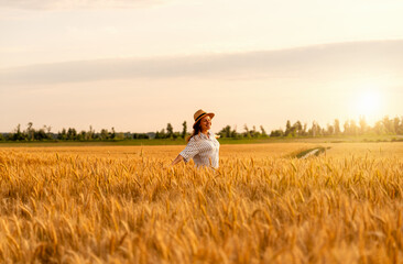 Happy woman enjoying rural nature in wheat field in countryside at golden hour