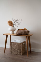 A beautifully minimalist wooden table showcasing ceramic white vase with dry flowers, branches,...