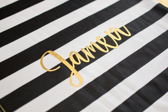 Gold Script Name " Jamelia" on Black and White Striped Fabric lettering