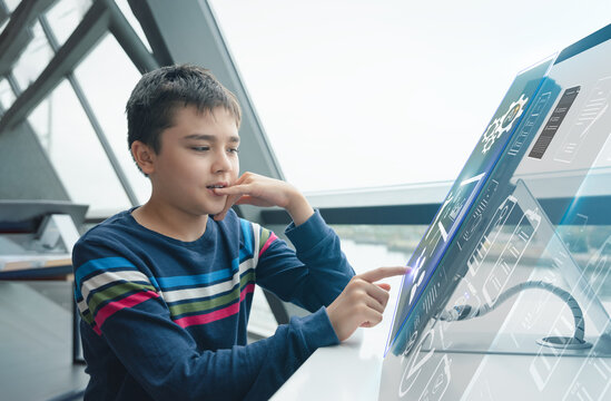 Education background,E - Learning School kid using futuristic digital touchscreen interface with holographic data display for studying at Modern High Tech classroom,Teen boy training online lesson - Powered by Adobe